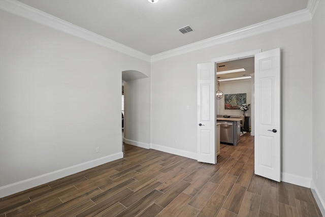 empty room with visible vents, arched walkways, crown molding, baseboards, and wood tiled floor