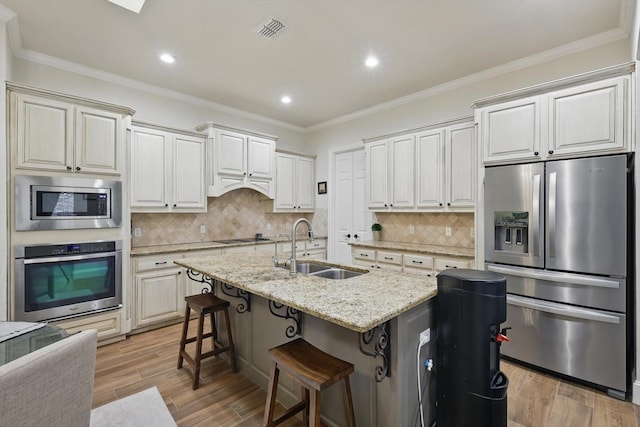 kitchen with a sink, crown molding, light wood-style flooring, and stainless steel appliances