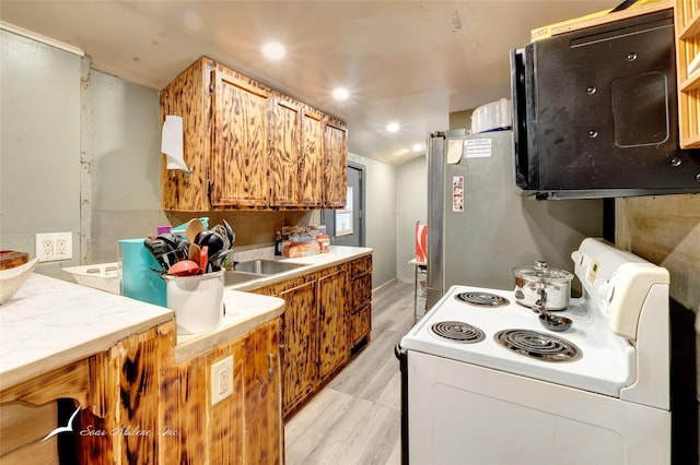 kitchen with white electric range oven, lofted ceiling, freestanding refrigerator, light countertops, and light wood-style floors