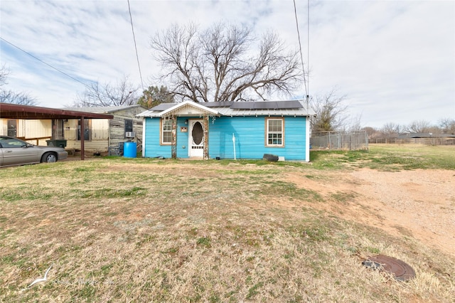 view of front of house featuring a front lawn, fence, an outbuilding, and a carport