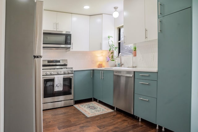 kitchen featuring dark wood-style floors, decorative backsplash, appliances with stainless steel finishes, and a sink