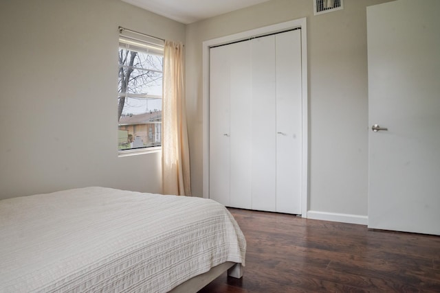 bedroom featuring visible vents, baseboards, a closet, and wood finished floors