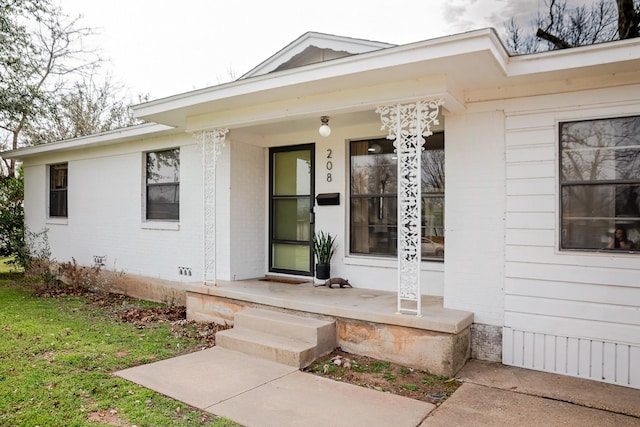 entrance to property featuring covered porch and brick siding