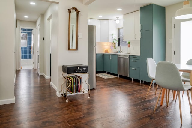 kitchen with green cabinetry, light countertops, dark wood-style floors, stainless steel appliances, and a sink