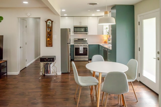 kitchen featuring visible vents, decorative light fixtures, backsplash, stainless steel appliances, and dark wood-style flooring