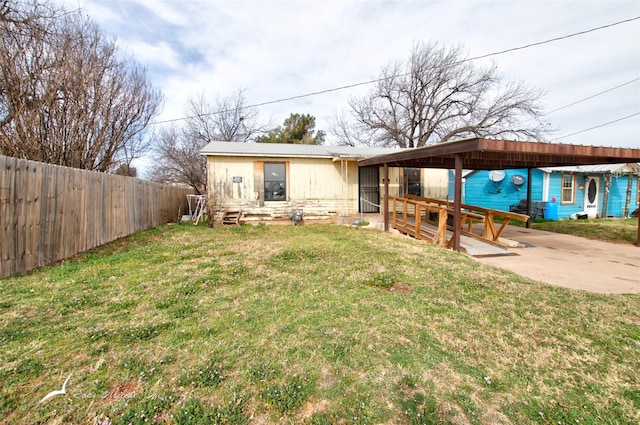 view of front facade featuring entry steps, a carport, a front yard, and fence