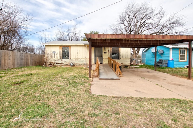 rear view of house with a lawn, a detached carport, entry steps, and fence