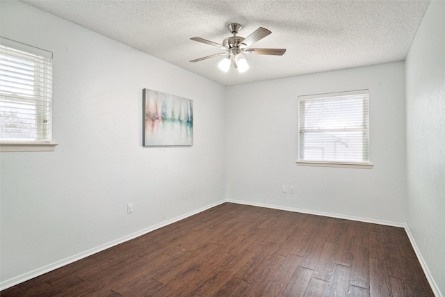 unfurnished room featuring dark wood-style floors, ceiling fan, baseboards, and a wealth of natural light