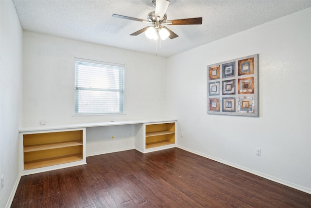 unfurnished room featuring a ceiling fan, a textured ceiling, wood finished floors, and built in desk