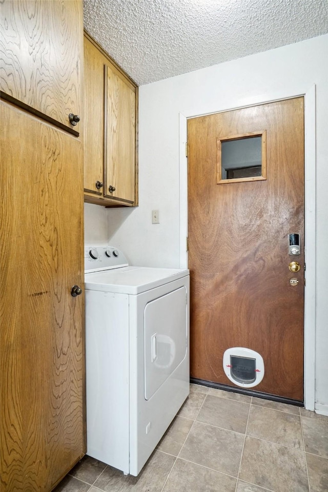 washroom with light tile patterned flooring, cabinet space, a textured ceiling, and washer / clothes dryer