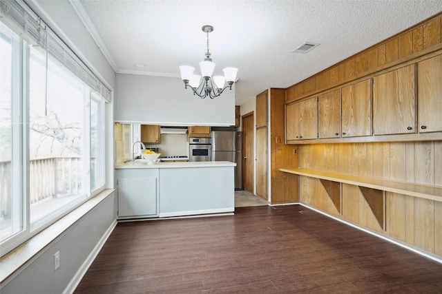 kitchen featuring visible vents, stainless steel appliances, dark wood-type flooring, a notable chandelier, and brown cabinets