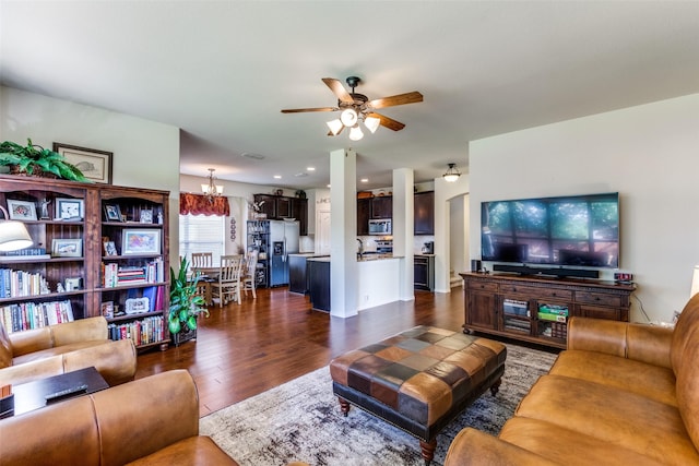 living room with visible vents, dark wood-type flooring, and ceiling fan with notable chandelier