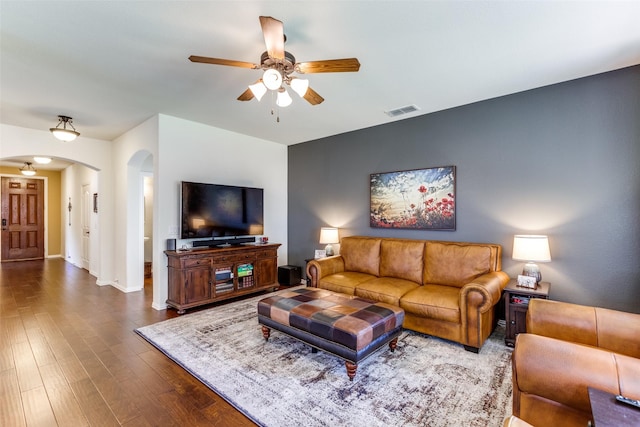 living area featuring visible vents, baseboards, ceiling fan, dark wood-style floors, and arched walkways