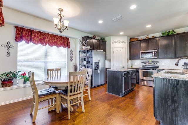 kitchen featuring visible vents, a sink, backsplash, appliances with stainless steel finishes, and light stone countertops