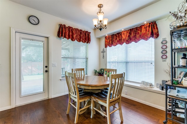 dining space featuring dark wood-style floors, a notable chandelier, and baseboards