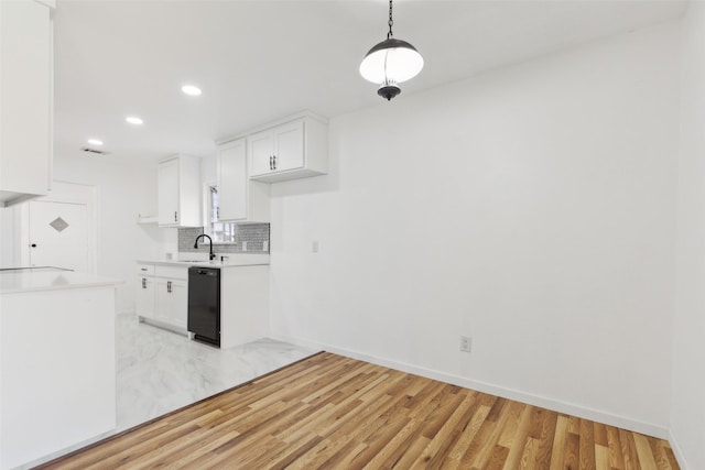 kitchen with tasteful backsplash, black dishwasher, white cabinets, and light countertops