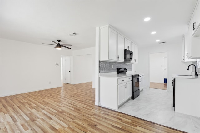 kitchen with visible vents, black appliances, a sink, backsplash, and light countertops