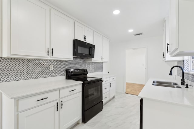 kitchen with black appliances, a sink, backsplash, white cabinets, and light countertops