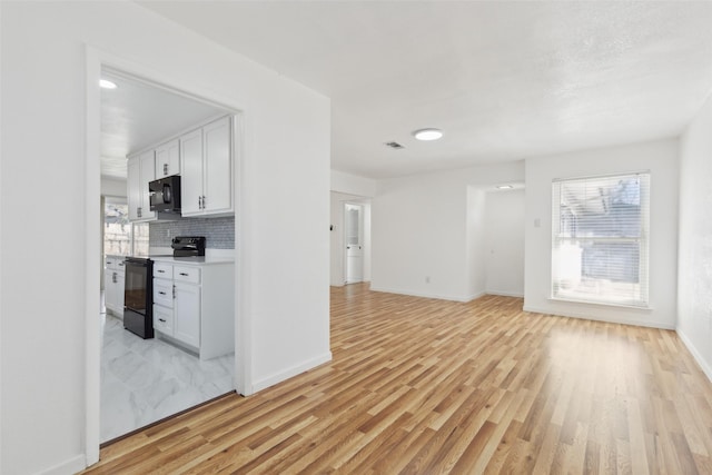 unfurnished living room with visible vents, light wood-style flooring, and baseboards