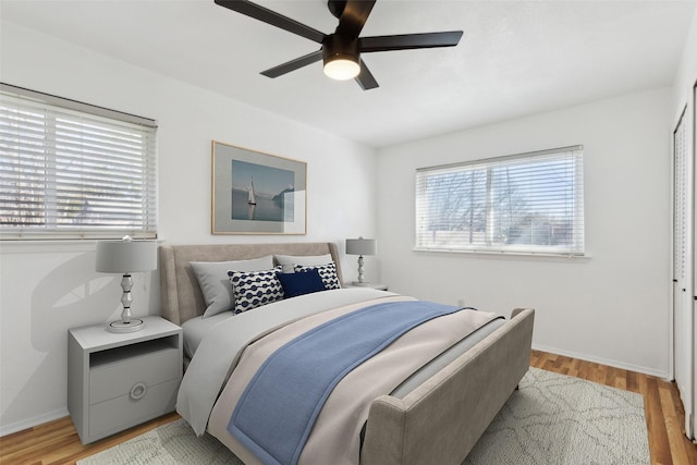 bedroom with baseboards, light wood-style floors, and a ceiling fan