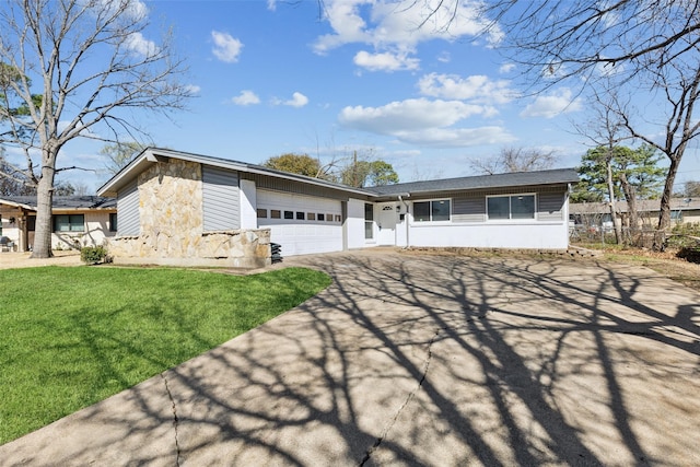 view of front of property with stone siding, a front yard, concrete driveway, and an attached garage