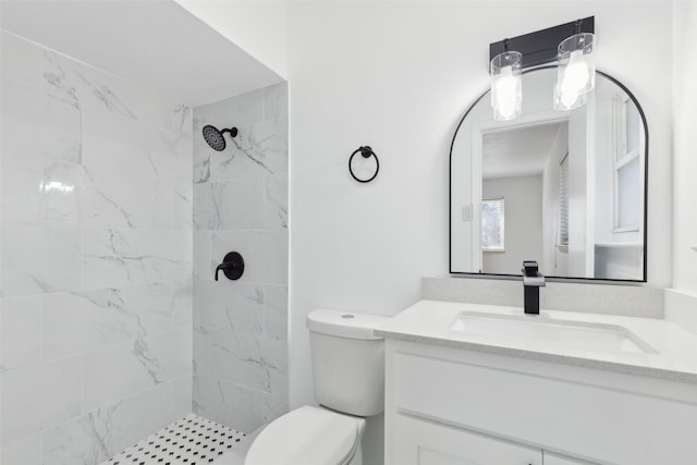 full bathroom with vanity, toilet, and tiled shower