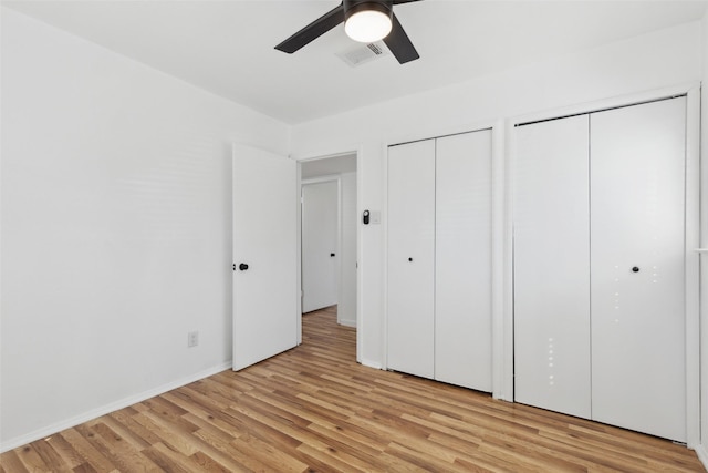 unfurnished bedroom featuring visible vents, ceiling fan, baseboards, multiple closets, and light wood-type flooring