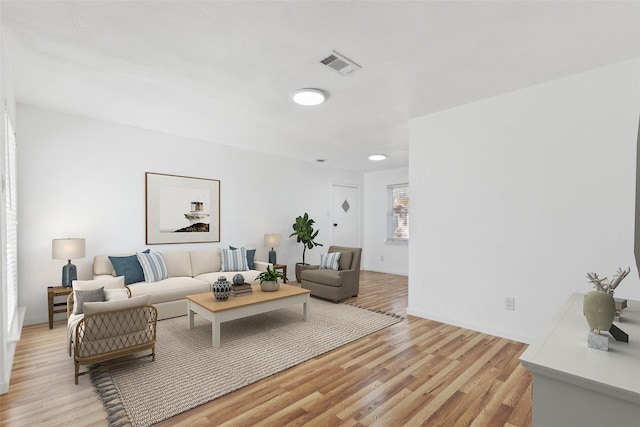 living area with light wood-style floors, visible vents, and baseboards