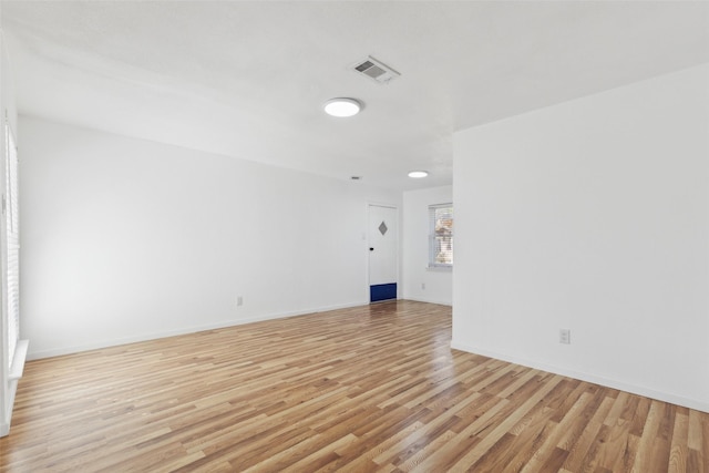 empty room featuring visible vents, light wood-style flooring, and baseboards