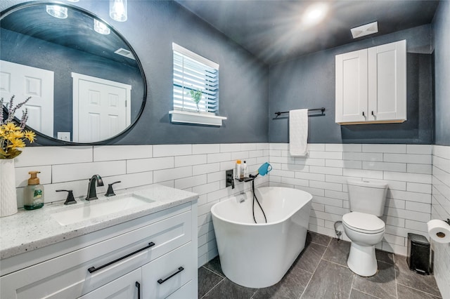 bathroom featuring vanity, visible vents, a freestanding tub, wainscoting, and toilet