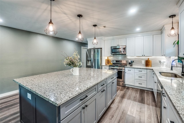 kitchen with a sink, decorative backsplash, dark wood-type flooring, appliances with stainless steel finishes, and a center island