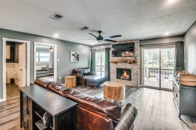 living area featuring ceiling fan, visible vents, wood finished floors, and a fireplace