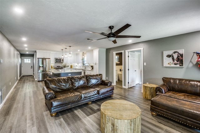 living room with visible vents, baseboards, ceiling fan, recessed lighting, and wood finished floors