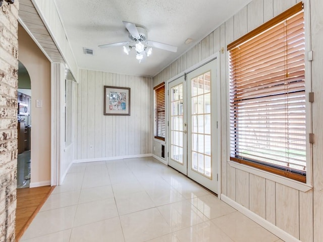 tiled spare room with visible vents, ceiling fan, french doors, arched walkways, and a textured ceiling