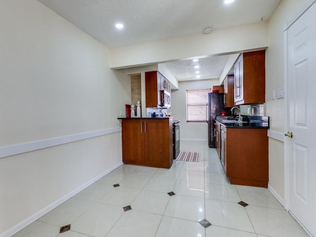 kitchen with light tile patterned floors, dark countertops, appliances with stainless steel finishes, and a textured ceiling