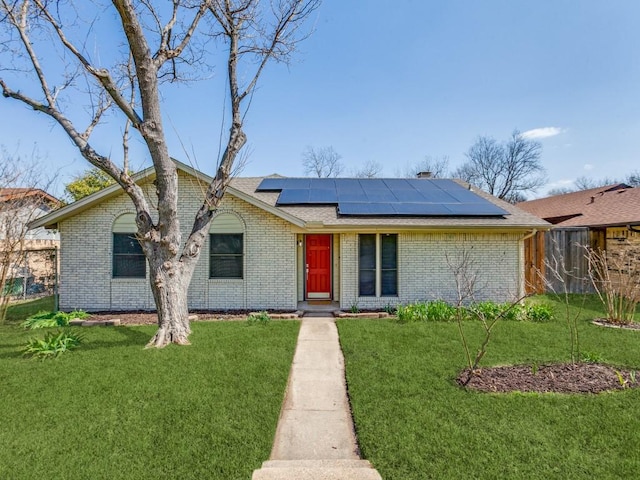 ranch-style house with brick siding, solar panels, and a front lawn