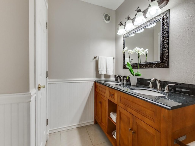 bathroom featuring a sink, double vanity, wainscoting, and tile patterned floors