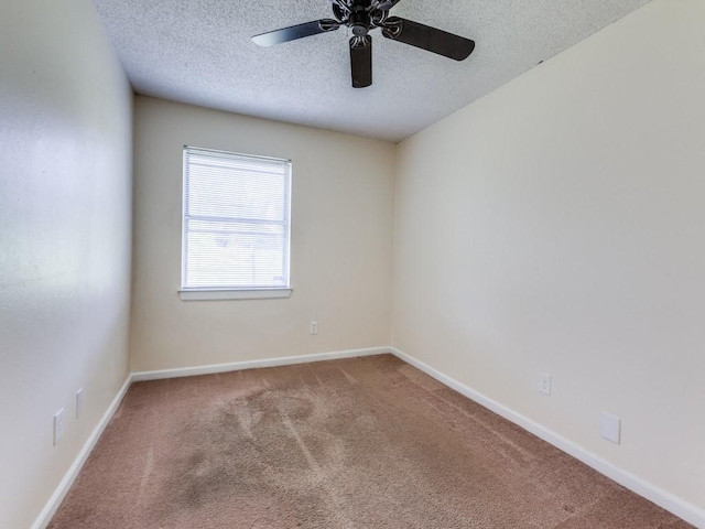 carpeted spare room featuring baseboards, a textured ceiling, and a ceiling fan