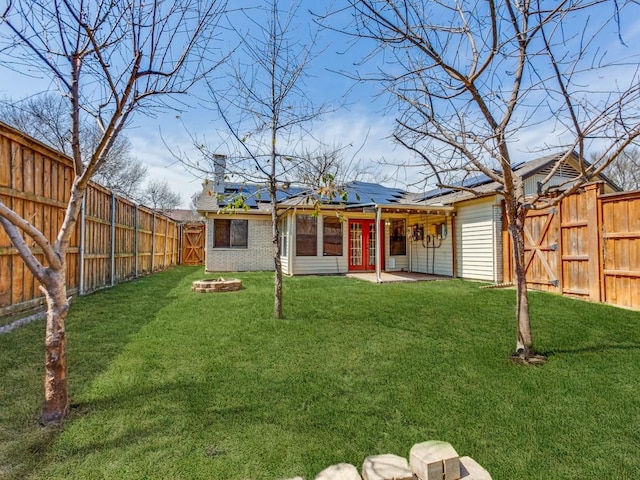 view of yard with a gate, french doors, and a fenced backyard