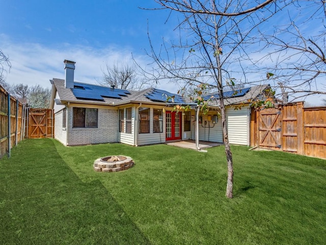 back of house featuring a fire pit, a fenced backyard, a lawn, and a gate