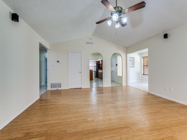 spare room with arched walkways, visible vents, a ceiling fan, and wood finished floors