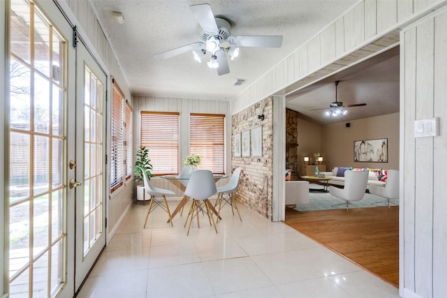 dining area featuring visible vents, a textured ceiling, french doors, tile patterned flooring, and ceiling fan