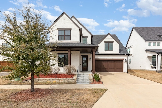 view of front of property with driveway, a porch, an attached garage, a shingled roof, and brick siding