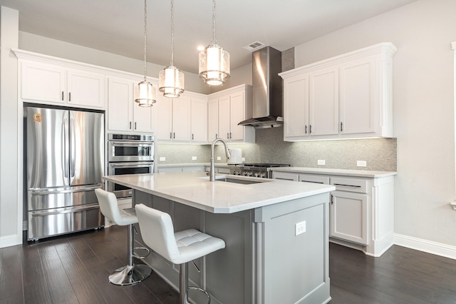 kitchen featuring stainless steel appliances, tasteful backsplash, wall chimney exhaust hood, and dark wood finished floors