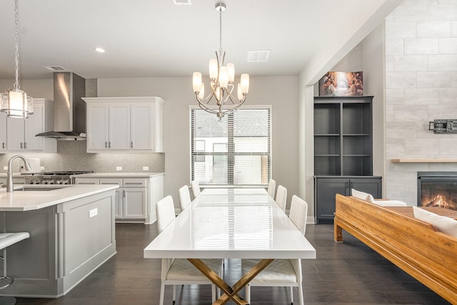 dining room with dark wood-style floors, a notable chandelier, a fireplace, and visible vents