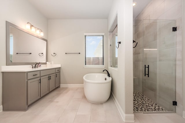 full bath with vanity, baseboards, a stall shower, a freestanding bath, and tile patterned floors