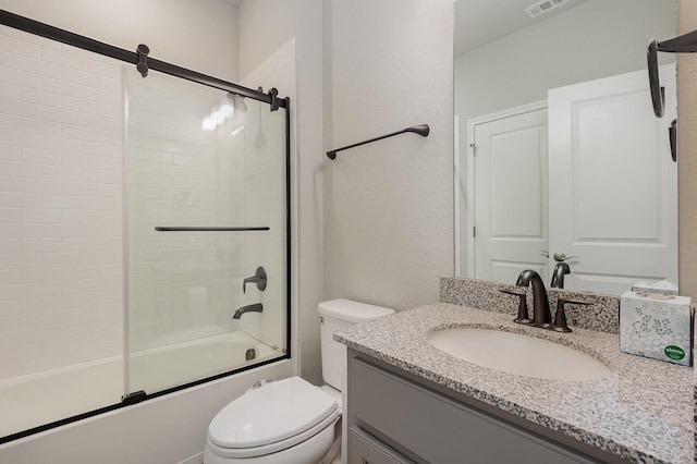 bathroom with vanity, toilet, visible vents, and shower / bath combination with glass door