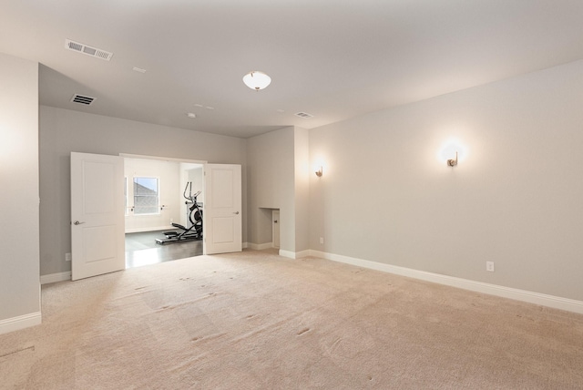 empty room featuring baseboards, visible vents, and light carpet