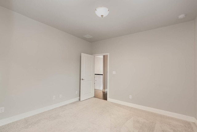 unfurnished room featuring light colored carpet and baseboards