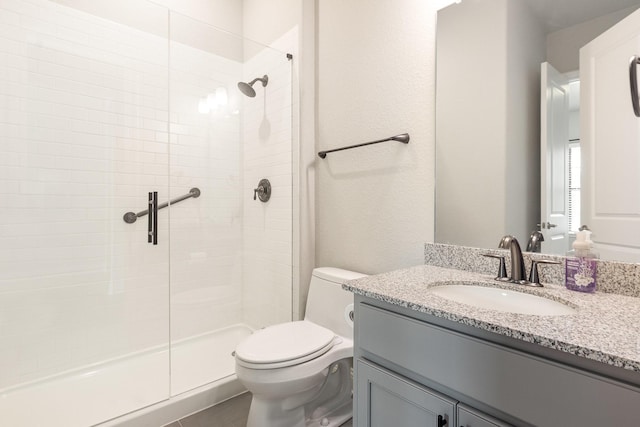 full bathroom featuring a stall shower, toilet, and vanity